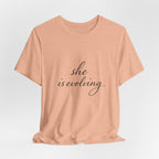 She Is Evolving Tee — Feminine Script Inspirational T-Shirt